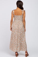 woman wearing a floral print maternity maxi dress with adjustable tie straps and a tiered skirt, showing a baby bump
