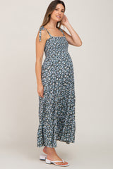 Pregnant woman wearing a blue floral smocked maternity maxi dress with tie straps and tiered skirt