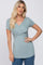 woman wearing a sage green short sleeve surplice maternity top with crossover front detail