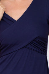 Close up of a navy blue wrap style maternity dress with a v-neckline and ruched side detailing