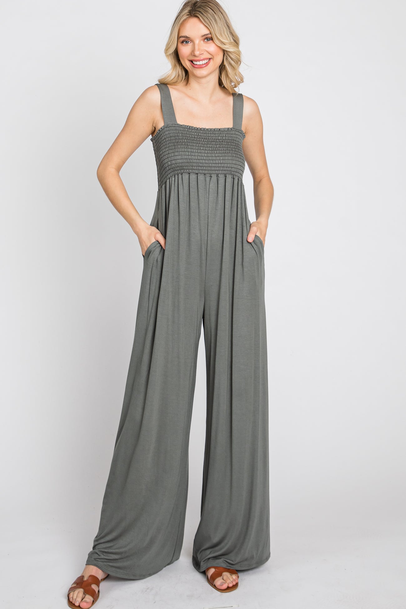 woman wearing a dark gray smocked bodice wide-leg jumpsuit with pockets