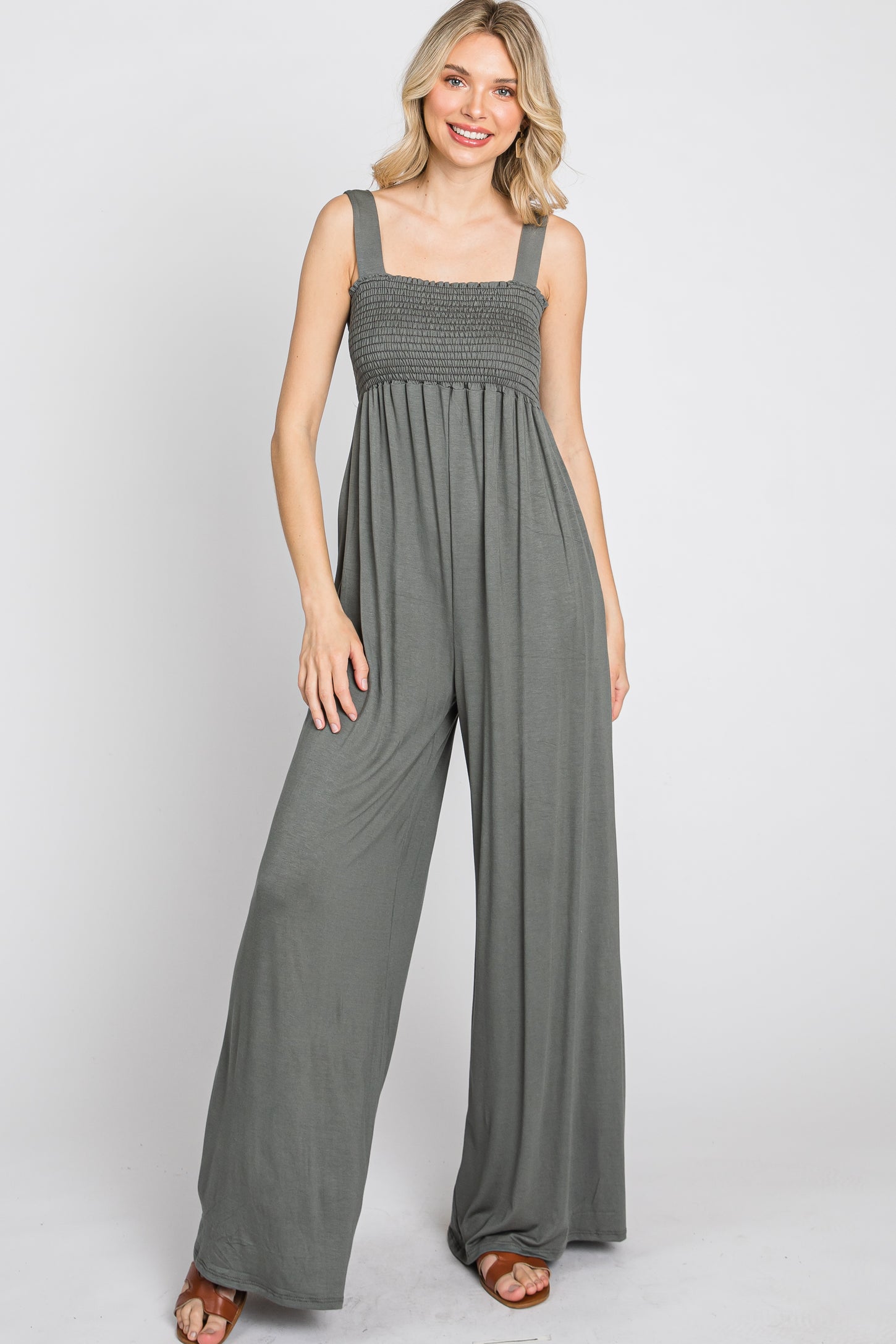 woman wearing a grey smocked wide-leg jumpsuit with a square neckline and thick straps