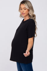 woman wearing a black short sleeve maternity top showing her baby bump