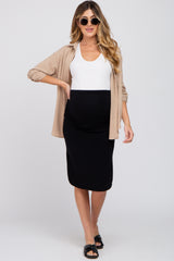 woman wearing a black maternity skirt and white tank top, styled with a beige shirt and sunglasses, and showcasing a baby bump