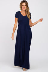 Woman wearing a navy blue short sleeve maternity maxi dress with a scoop neckline and empire waist