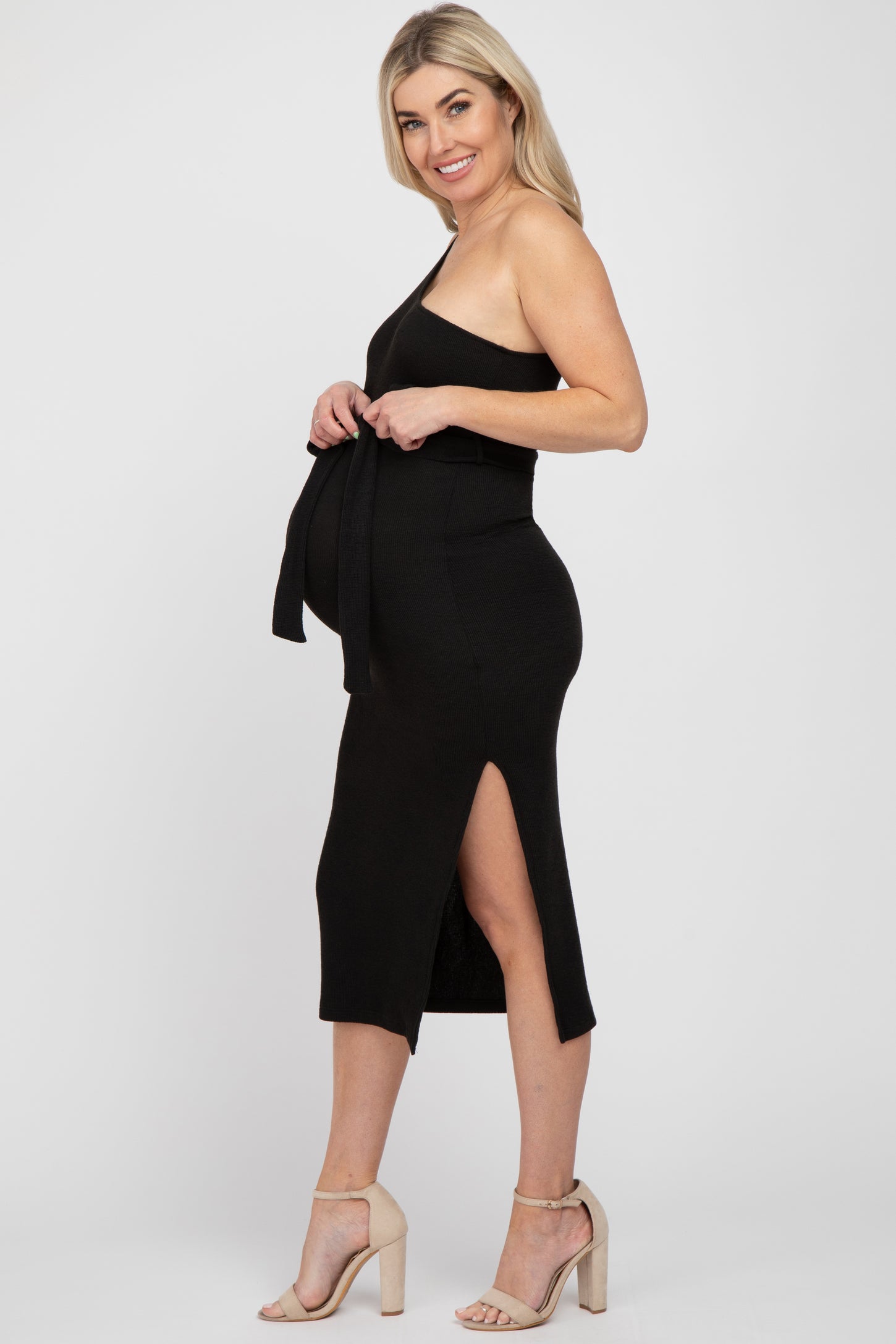 woman wearing a black ribbed maternity dress with a side slit and tie detail, showcasing her baby bump