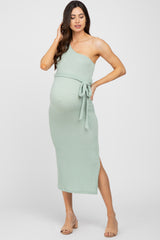 woman wearing a light green ribbed one-shoulder maternity dress with a tie at the waist and a visible baby bump