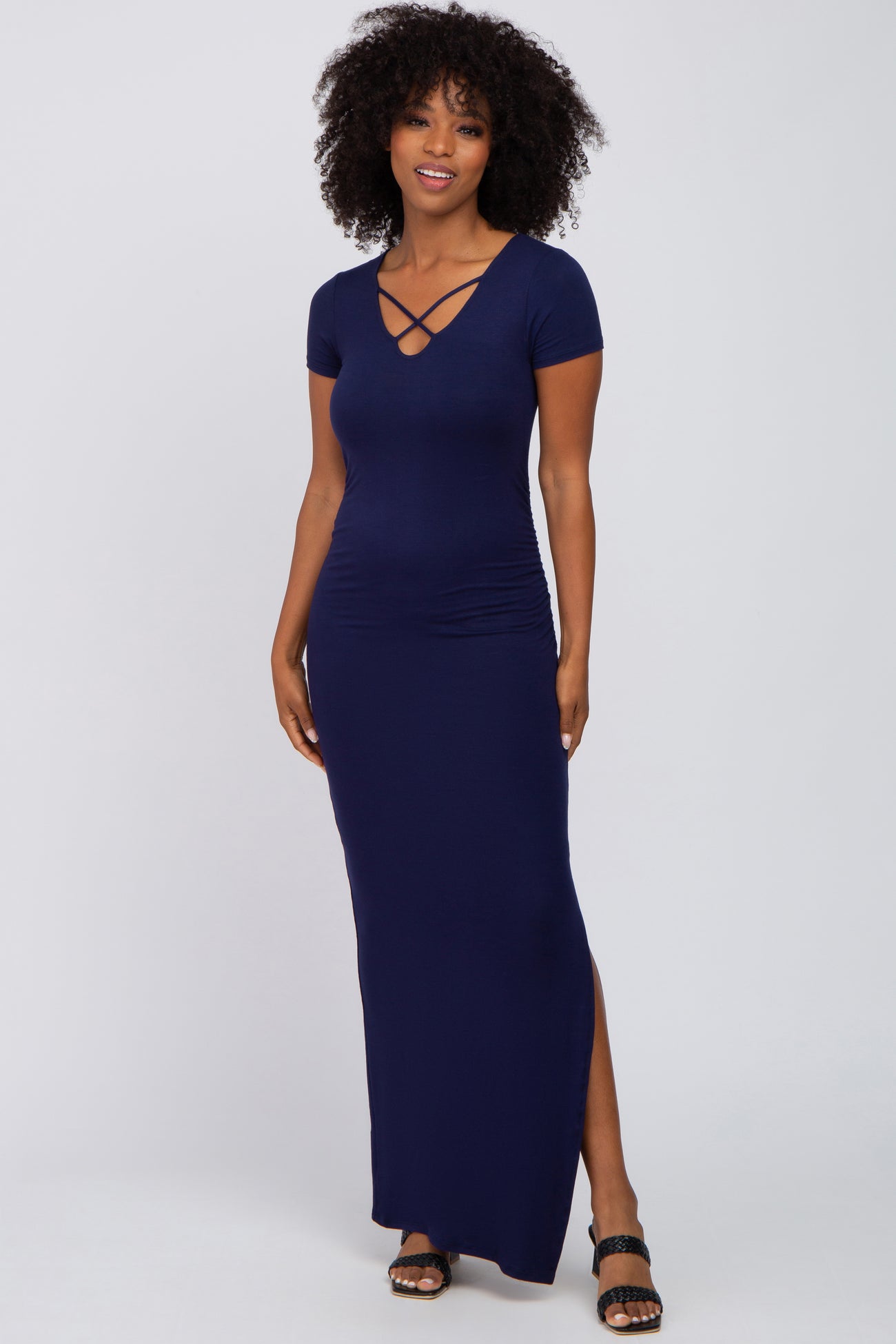 woman with curly hair wearing a navy blue short sleeve maxi dress with a crisscross neckline