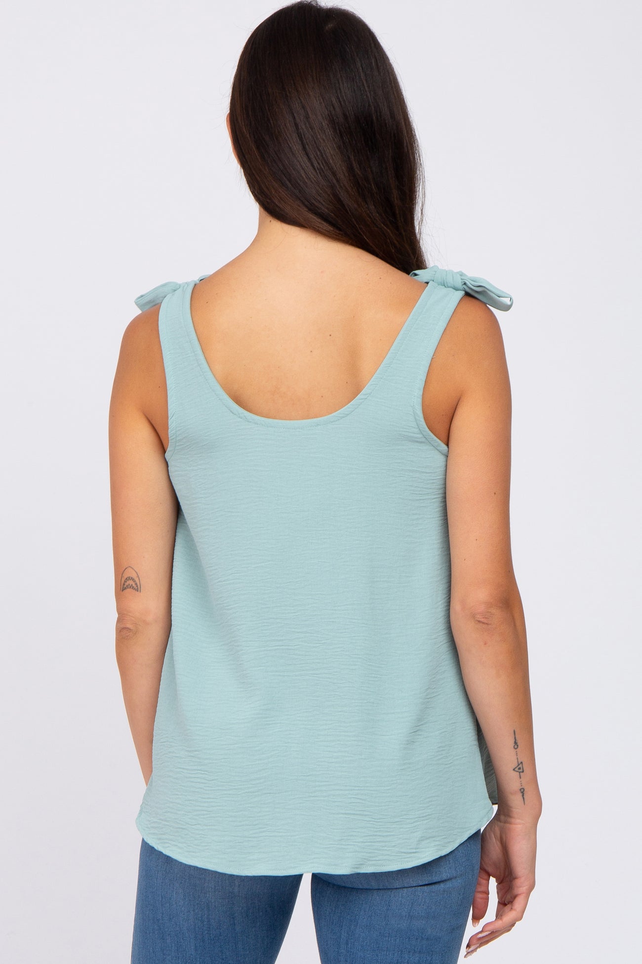woman wearing a light blue sleeveless top with tie shoulder straps, viewed from the back