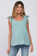 woman wearing a light teal sleeveless maternity top with tie shoulder details and a relaxed fit