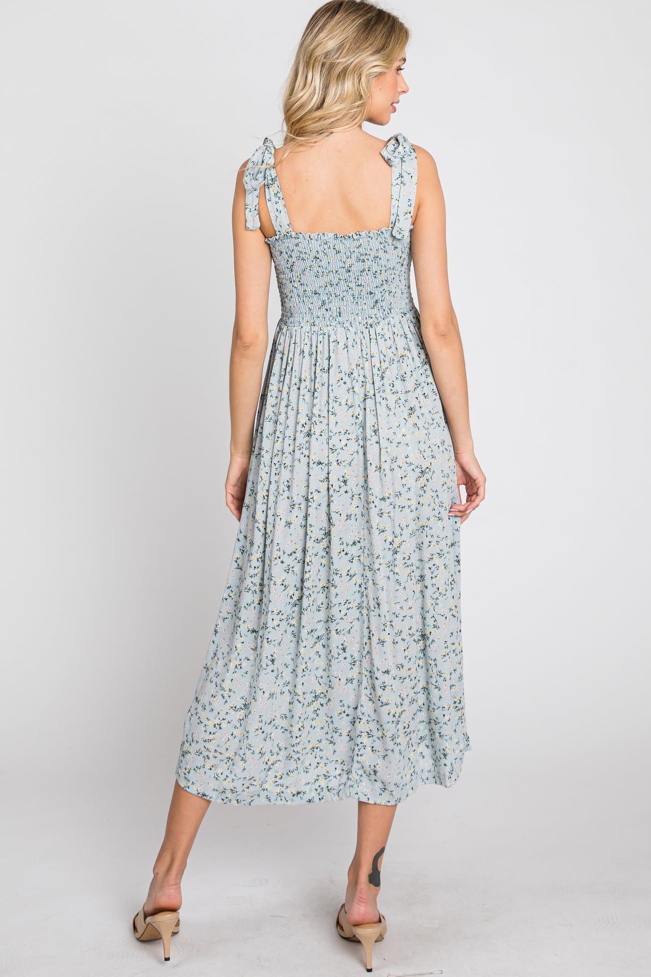 Back view of woman in light blue floral midi dress with smocked bodice and tie straps