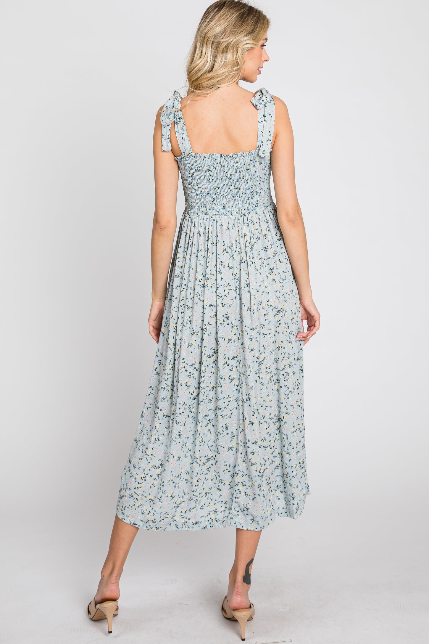 Back view of woman in light blue floral midi dress with smocked bodice and tie straps