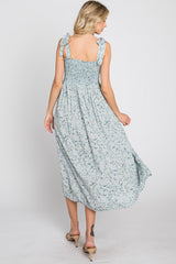 woman wearing a light blue floral maxi dress with smocked back and tie straps, turning to showcase the back view
