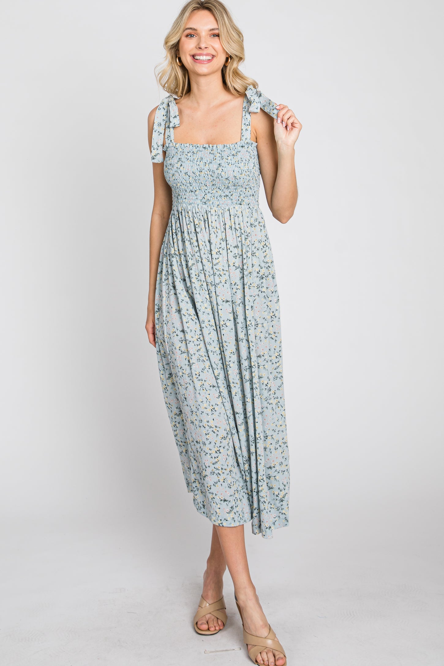 woman wearing a light blue floral maxi dress with smocked bodice and tie straps