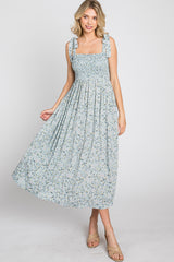 woman wearing a light blue floral maxi dress with smocked bodice and ruffled straps