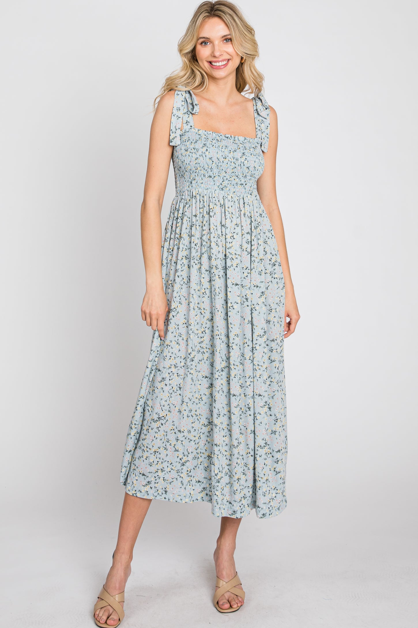 woman wearing a light blue floral midi dress with square neckline and tie straps