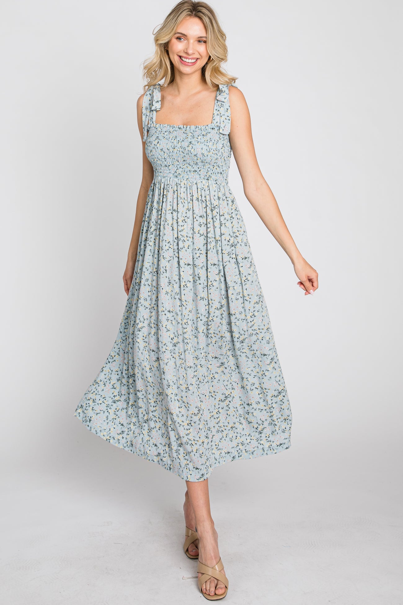 woman wearing a light blue floral midi dress with smocked bodice and tie straps