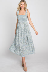 woman wearing a light blue floral midi dress with smocked bodice and tie straps