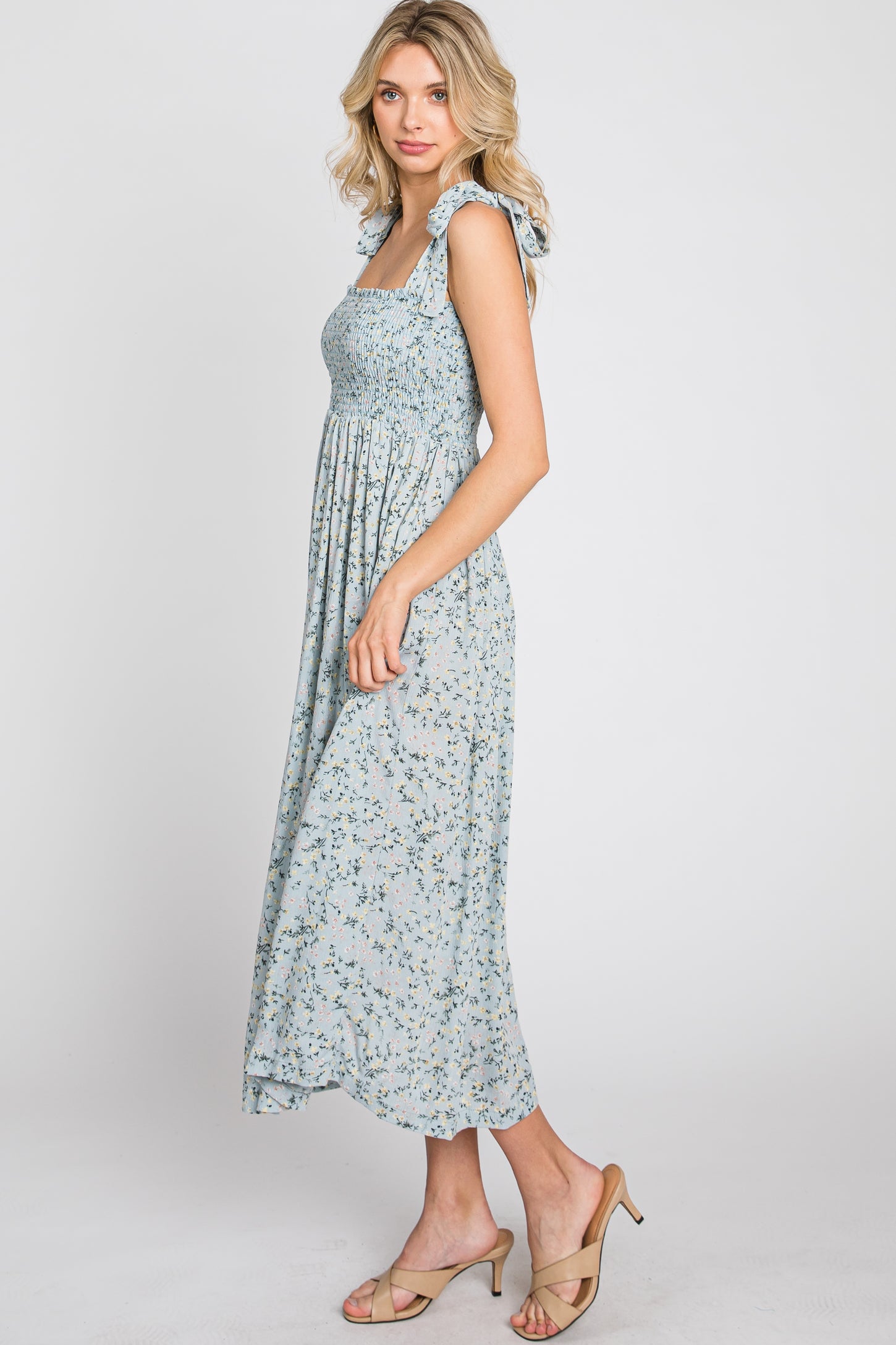 woman wearing a light blue floral midi dress with smocked bodice and ruffle straps