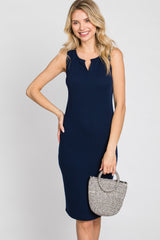 woman wearing a navy blue sleeveless ribbed midi dress with a keyhole neckline, holding a small handbag