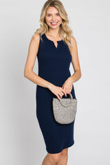 woman wearing a navy blue sleeveless ribbed dress with a keyhole neckline, holding a small textured handbag