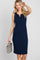 woman wearing a navy sleeveless ribbed dress with a keyhole neckline and holding a small woven handbag