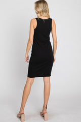 Back view of a woman wearing a sleeveless black ribbed midi dress and beige block heel sandals