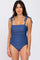 woman wearing a blue one-piece swimsuit with ruched detailing and tie-shoulder straps