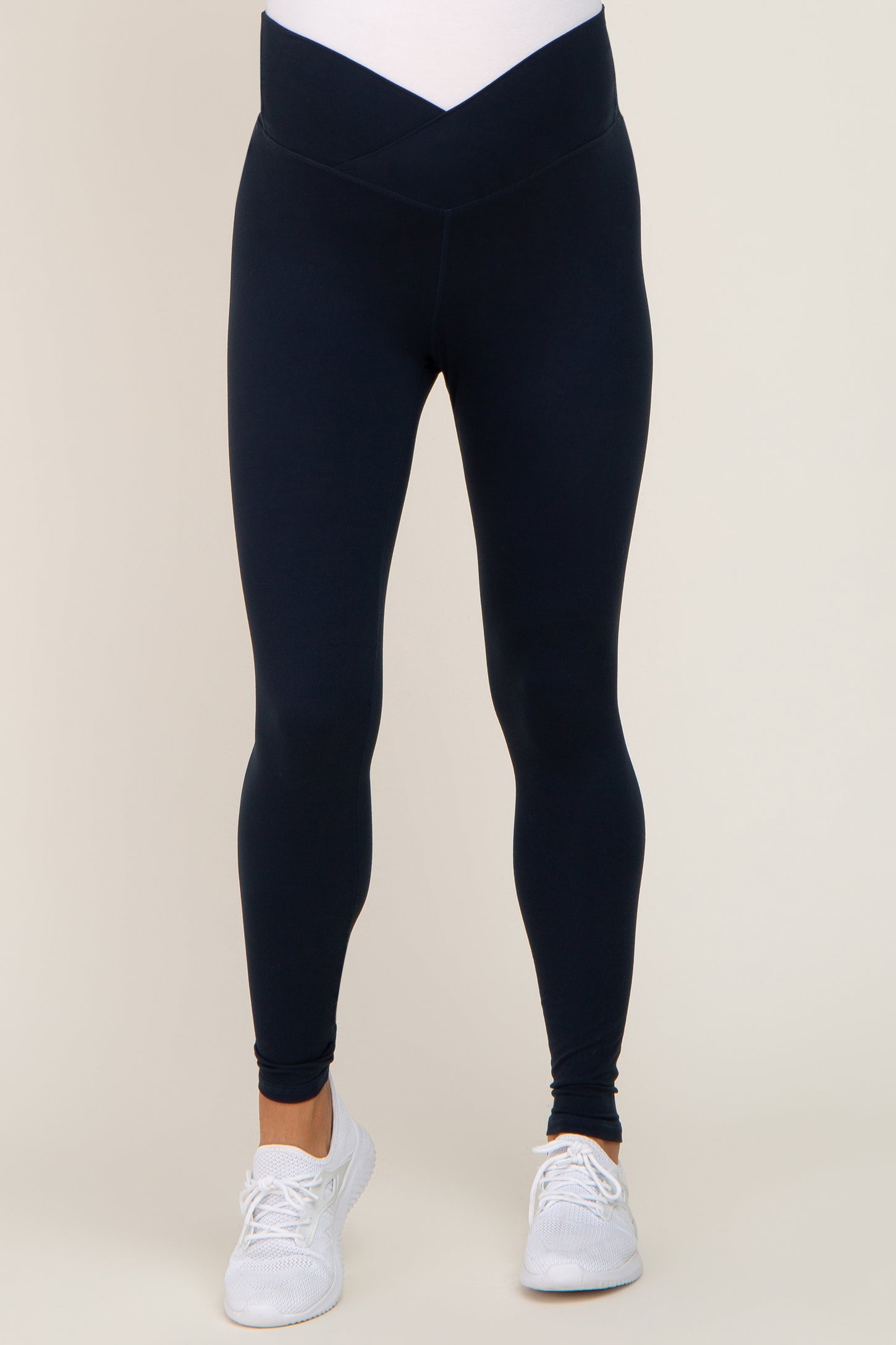 woman wearing navy maternity leggings with a v-shaped waistband and ankle length, styled for comfort