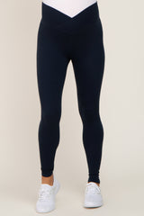 woman wearing navy maternity leggings with a v-shaped waistband and ankle length, styled for comfort
