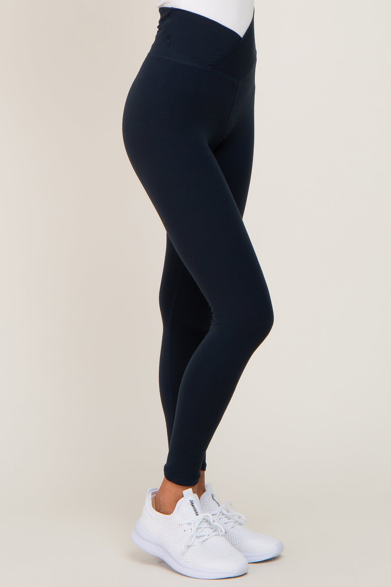 woman wearing high-waisted navy leggings and white athletic shoes