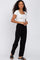 woman wearing a white square neck fitted top and black wide-leg pants, standing with one hand on her hip