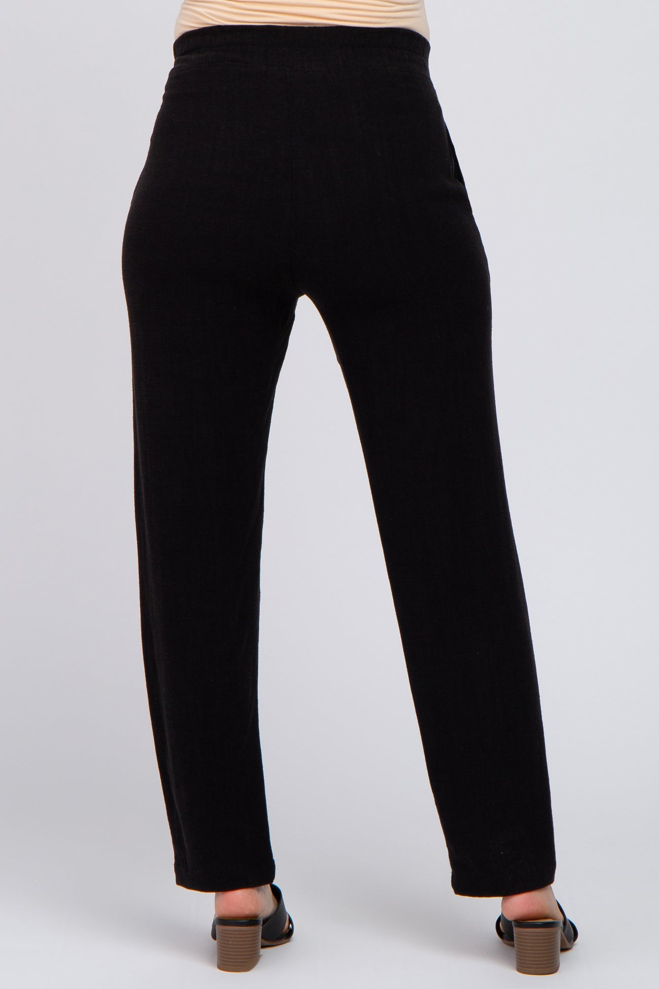 woman wearing black maternity pants, shown from the back, featuring a relaxed fit and subtle texture