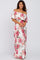 woman wearing a white off-the-shoulder maxi dress with pink floral print and ruffled sleeves