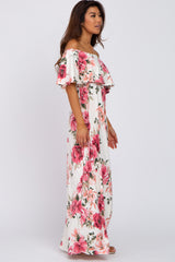 woman wearing a white off-the-shoulder floral maxi dress with pink roses and layered ruffle detail