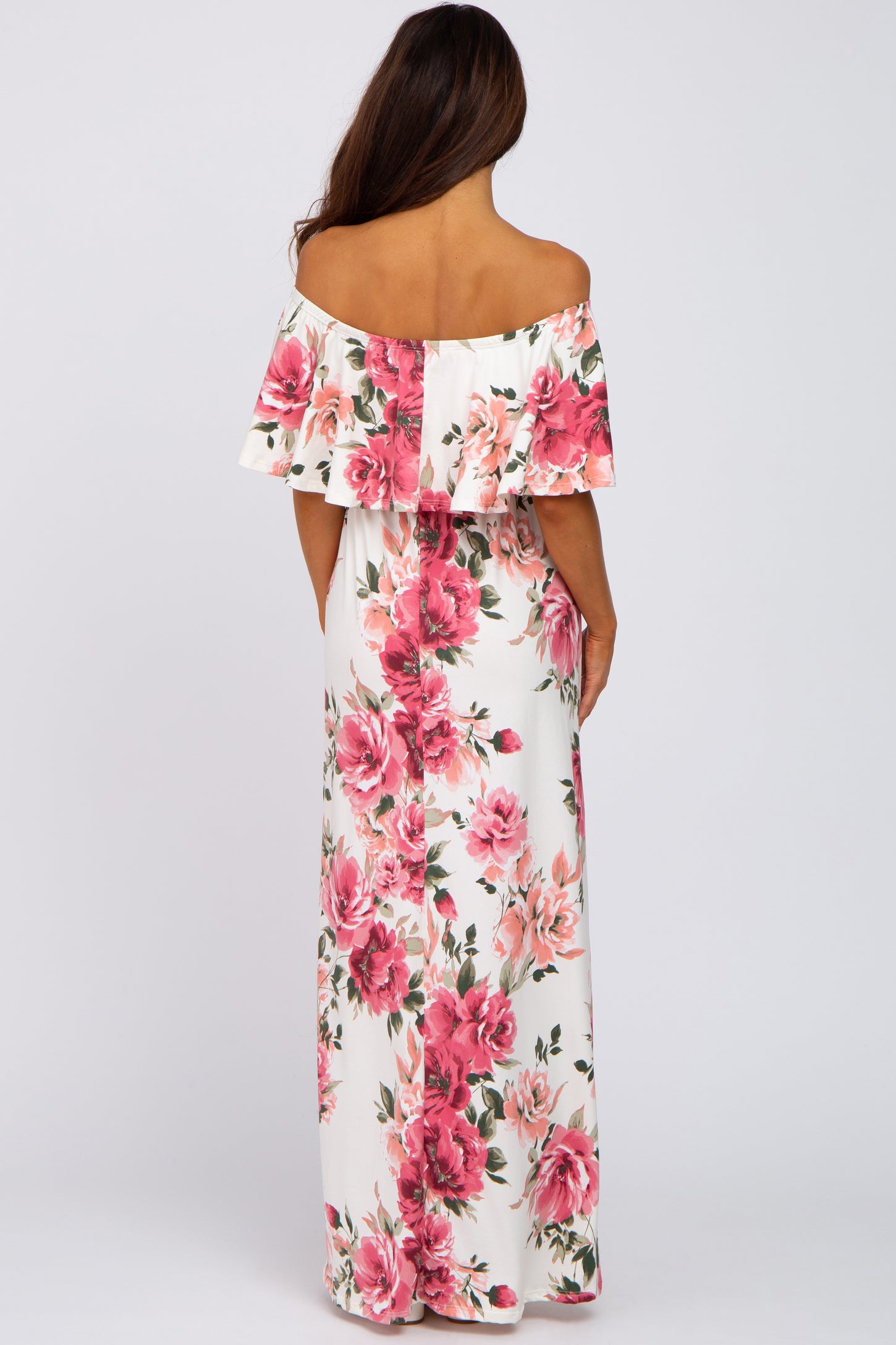woman wearing a white off-the-shoulder maxi dress with pink floral print, seen from the back