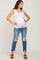 woman wearing a white maternity tank top and distressed blue maternity jeans, showcasing her baby bump