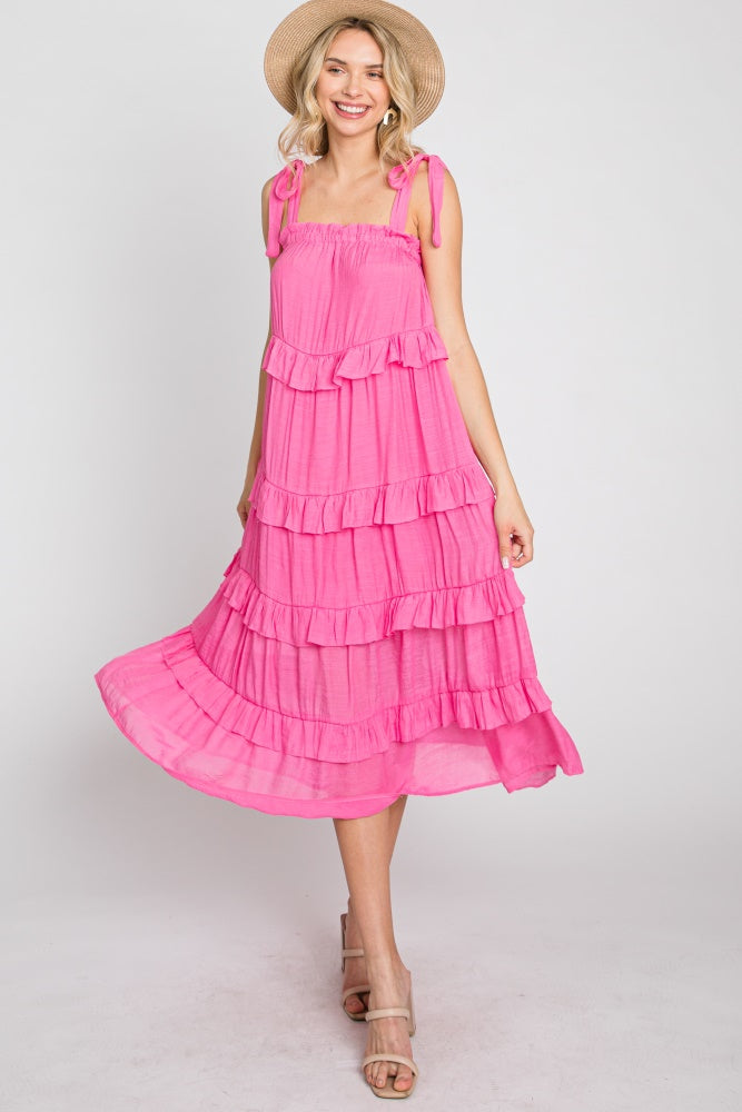 woman wearing a hot pink tiered midi dress with tie straps and a straw hat