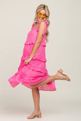 woman in a pink tiered maternity midi dress with tie straps and yellow sunglasses