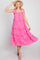 woman wearing a hot pink tiered ruffle midi dress with tie straps and a straw hat