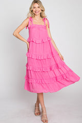 woman wearing a hot pink tiered midi dress with tie straps and ruffle details