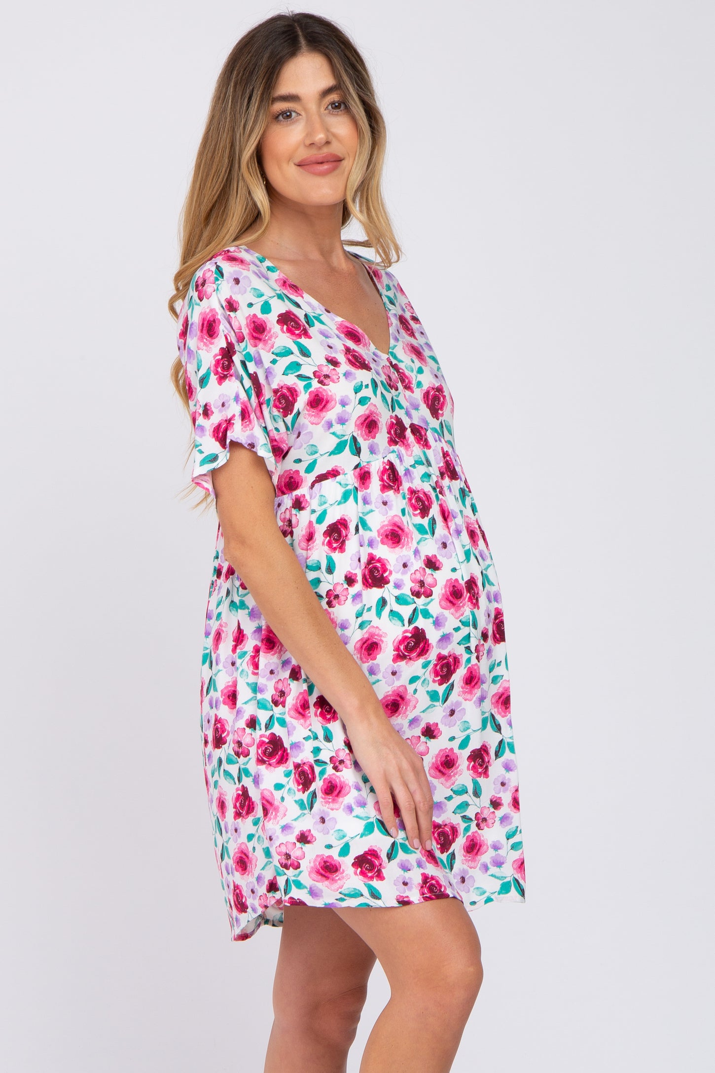 pregnant woman wearing a short sleeve floral maternity dress with pink and purple roses