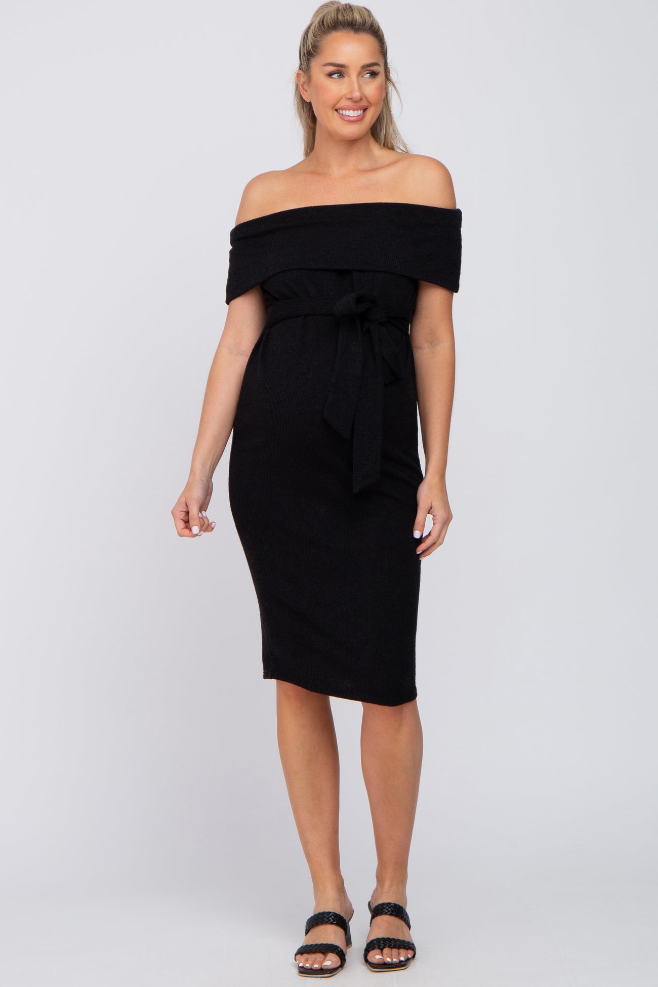 woman wearing a black off-the-shoulder maternity dress with a tie waist and a visible baby bump