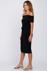 woman wearing a black off-the-shoulder midi dress with a waist tie and snakeskin print sandals