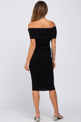 woman wearing a black off-the-shoulder midi dress, standing with her back to the camera