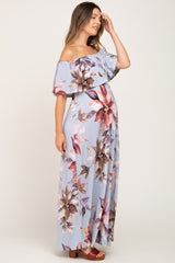 woman wearing a light blue floral off-shoulder maternity dress with a flowing design and visible baby bump