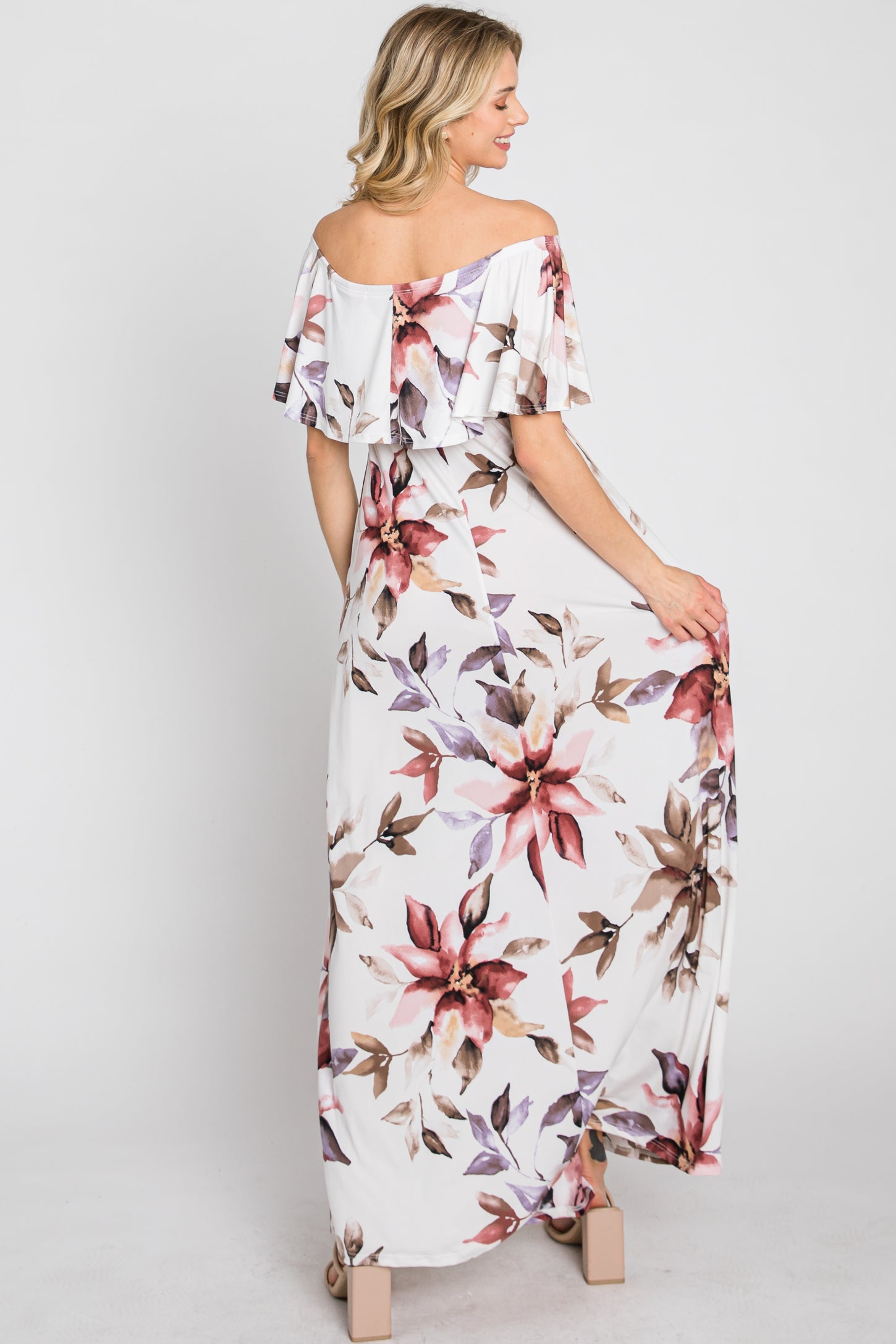 woman wearing a white floral off-the-shoulder maxi dress with ruffle details, showing the back view