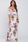 woman wearing a floral off-the-shoulder maxi dress, showcasing a baby bump, in a light color palette with pink and purple accents