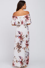 woman wearing a floral off-the-shoulder maxi dress in white with pink and mauve accents, showing a baby bump