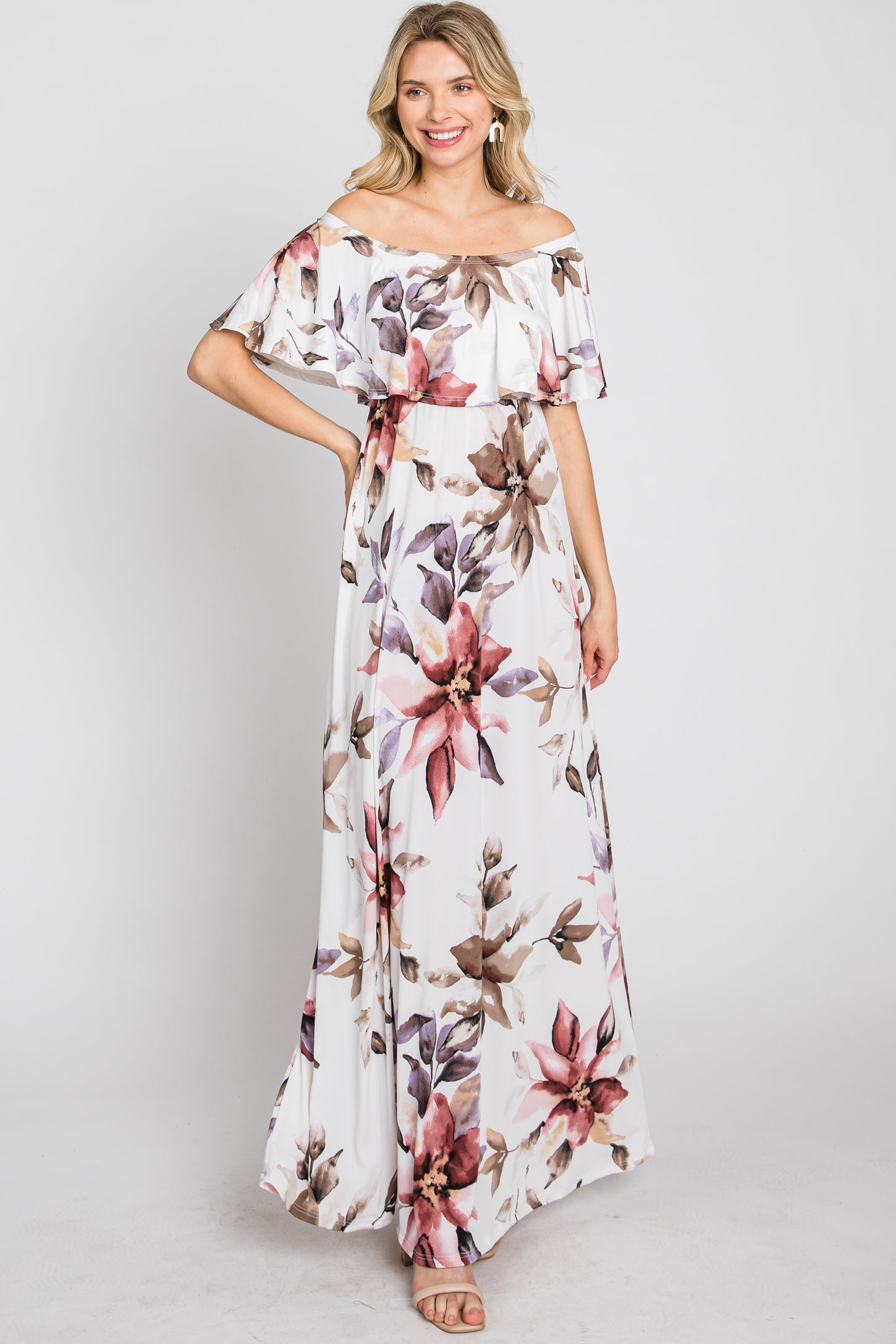 woman wearing a white off-the-shoulder maxi dress with a large floral print in shades of pink and purple